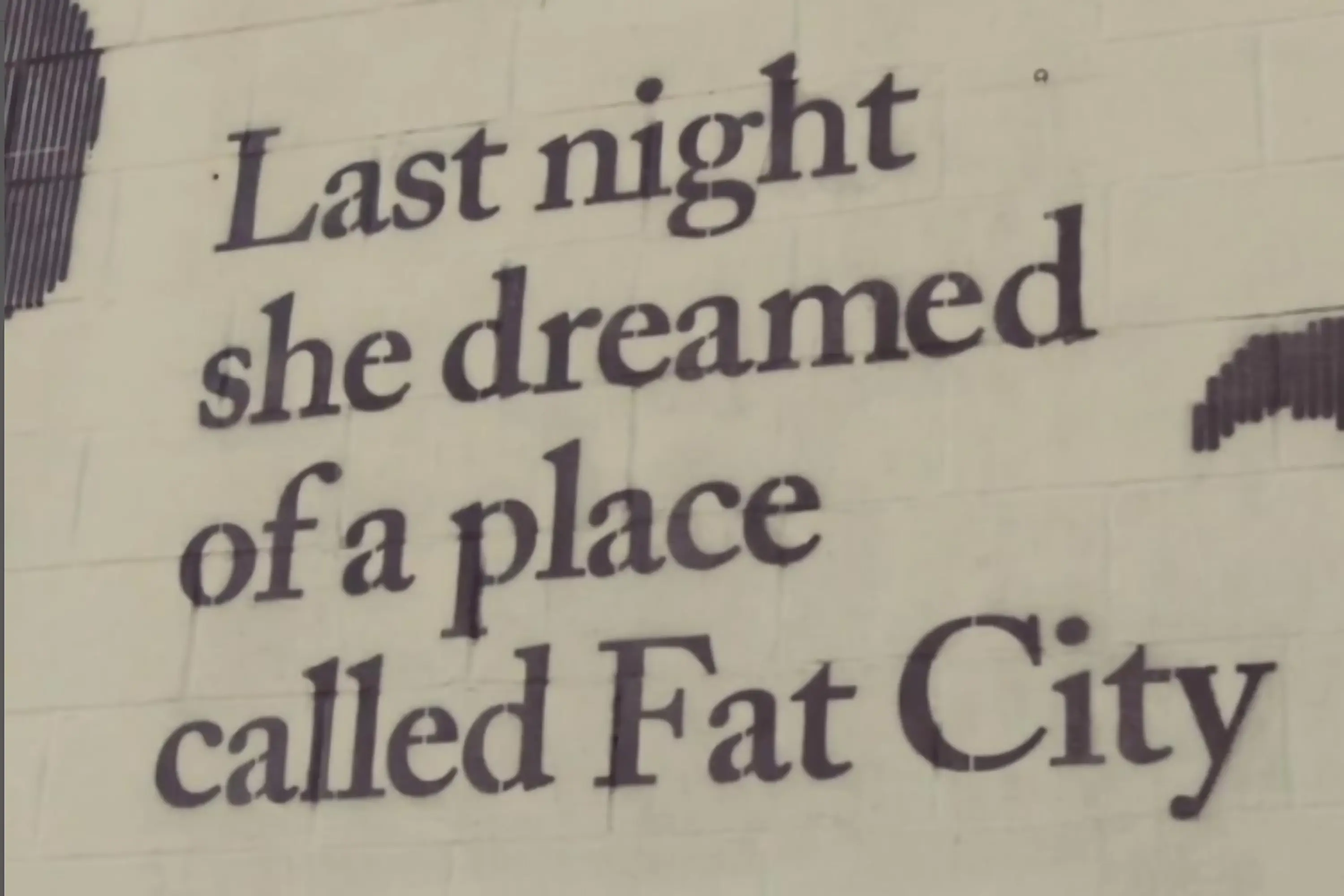 A mural stating "Last night she dreamed of a place called Fat City"